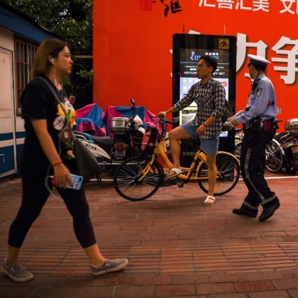 A traffic police officer prepares to talk to a man on a bicycle near a facial recognition screen at an intersection in Shanghai. (Picture: AFP)