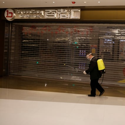 A shopping mall worker carrying sanitizing equipment outside a closed cinema in Beijing on February 3. (Picture: Carlos Garcia Rawlins/Reuters)