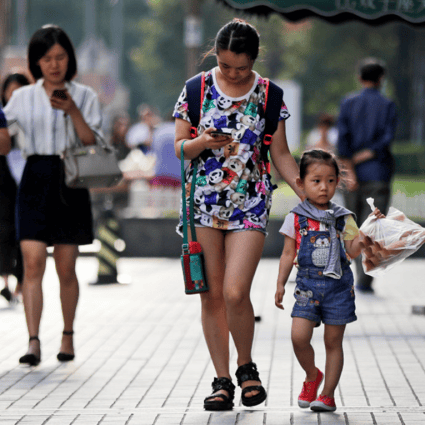Pedestrians view their smartphones on a sidewalk in Beijing. (Picture: Andy Wong/AP Photo)