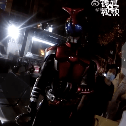 Kamen Rider (right) was unable to pass through a community checkpoint until he could get his smartphone out. (Picture: Zhejiang TV via Weibo)