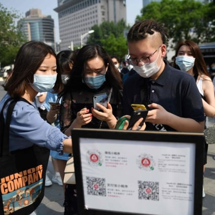 People use QR codes required to prove their health and travel status before being allowed to enter a shopping mall in Beijing on May 2, the second day of a five-day national holiday. (Picture: AFP)