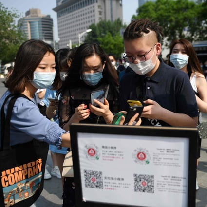 People scan a code to bring up a phone app that generates a health code before they enter a shopping mall in Beijing on May 2. (Picture: Greg Baker/AFP)