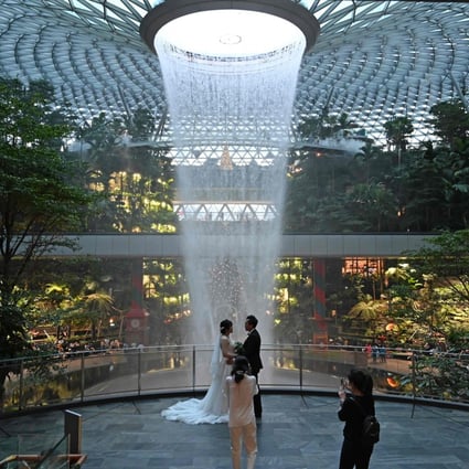 A newly-wedded couple poses for their photographer against the Rain Vortex at Changi Jewel in Singapore in December, 2020. Photo: AFP