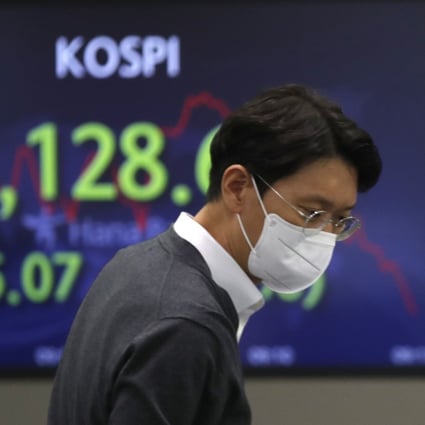 A currency trader walks near a screen showing the Korea Composite Stock Price Index at a foreign exchange dealing room in Seoul on February 18. Photo: AP 
