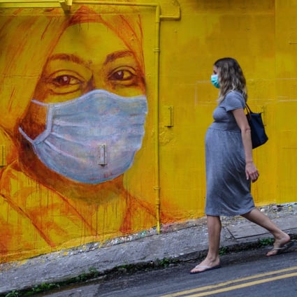 A pregnant woman walks past a street mural in Hong Kong in March last year. Actions that benefit Hong Kong’s women and girls will ripple out to enhance the well-being of the whole of society. Photo: AFP 