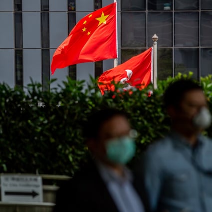 Pedestrians wearing protective masks walk past the Chinese and Hong Kong Special Administrative Region flags flying outside the government headquarters in Admiralty. Photo: Bloomberg