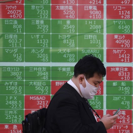 A man walks by an electronic stock board of a securities firm in Tokyo on March 10. Record runs in the US keep Asian markets on the front foot amid recovery outlook. Photo: AP