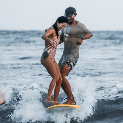 Chinese surfer Monica Guo and surfing instructor Justin Tian share a surfboard in Hainan, China. Women make up almost three quarters of the clientele at surf schools run by Tian. Photo: Courtesy of Justin Tian