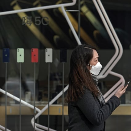 A woman passes an Apple store displaying iPhones at a shopping mall in Beijing, China. Photo: AP Photo