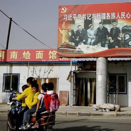 An Uygur woman on a scooter fetches school children as they ride past a picture of China’s President Xi Jinping joining hands with a group of Uygur elders in 2018. Photo: AP