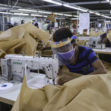 A man wearing face mask and face shield to help curb the spread of the new coronavirus, sews surgical gown at a garment factory in Yangon, Myanmar. Garment workers in Myanmar are urging major international brands to denounce the recent military coup there and put more pressure on factories to protect workers from being fired or harassed. Photo:AP