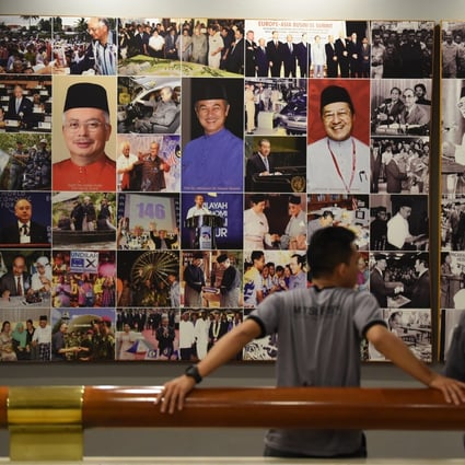 Two men stand in front of a wall of pictures of Malaysian leaders at the Umno headquarters in Kuala Lumpur. Photo: AFP