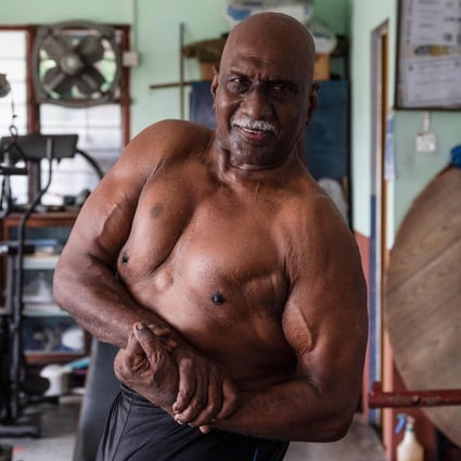 Malaysian bodybuilder A. Arokiasamy flexes his muscles after training at his gym in Teluk Intan, Perak, Malaysia. He still pumps iron every day, and believes staying healthy through a vigorous fitness routine is the best defence against coronavirus. Photo: AFP