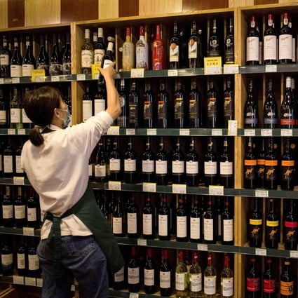 An employee placing a bottle of wine next to Australian made wine (R) at a store in Beijing on August 18, 2020. Photo: AFP