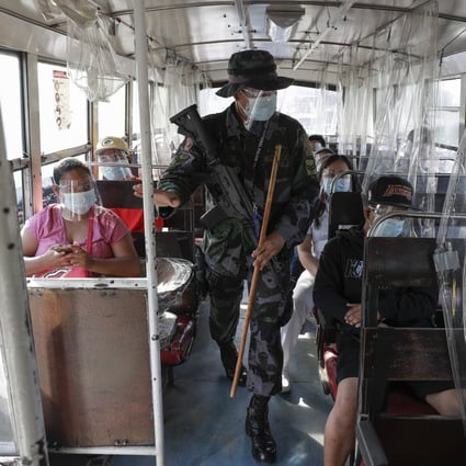 An armed policeman checks a passenger bus during the new lockdown to prevent the spread of Covid-19 in Metro Manila. Photo: AP
