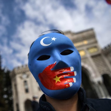 A demonstrator wearing a mask painted with the colours of the flag of East Turkestan takes part in a protest in Istanbul on Thursday. Photo: AFP