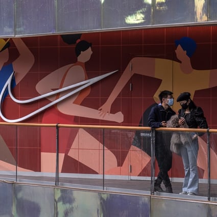 People stand in front of a Nike store in the Sanlitun shopping area of Beijing on March 27. After H&M and Nike, many other international clothing brands have faced a backlash in China for refusing to buy Xinjiang cotton over claims of forced labour and repressions against Uygurs in the region. Photo: EPA-EFE 
