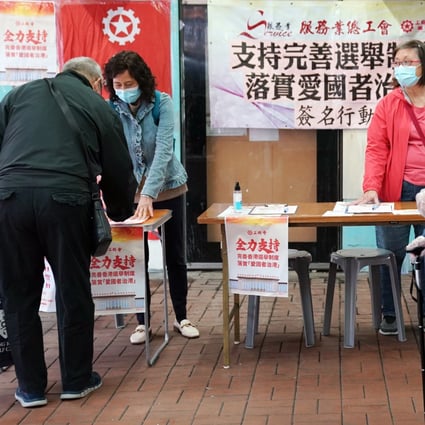 A passerby signs his support for improving the electoral system of the Hong Kong Special Administrative Region and implementing the principle of “patriots administering Hong Kong”, on March 7. Photo: Xinhua
