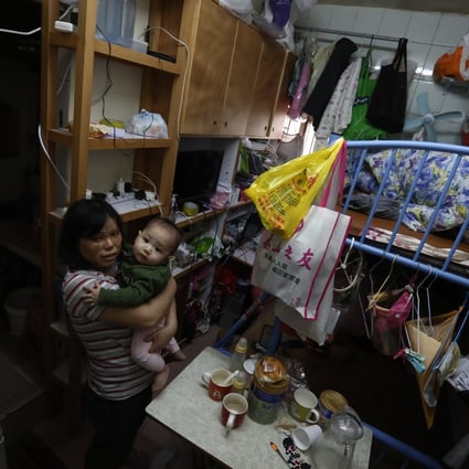 A mother holds her baby in a 100 sq ft subdivided unit in Cheung Sha Wan that they share with two other family members, on March 24. Photo: Jonathan Wong