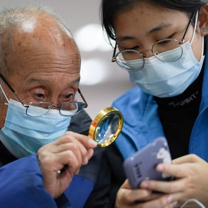 A student volunteer from Beijing Foreign Studies University demonstrates for a senior citizen how to make a hospital appointment using a mobile phone.Photo: Xinhua