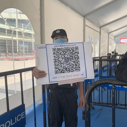 A security guard holds a sign with a QR code for visitors to scan and download a new official anti-fraud app at the entrance of the Shenzhen Convention and Exhibition Center on April 12, 2021. Photo: Yujie Xue