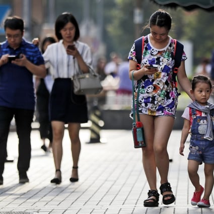 Pedestrians view their smartphones as they walk along a sidewalk in Beijing on Wednesday, Aug. 9, 2017. Photo:: AP