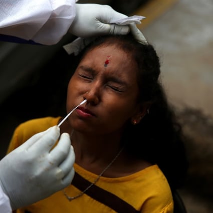 An Indian health worker collects a nasal swab sample from a woman in Bangalore. Photo: EPA