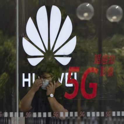 A worker wearing a mask speaks on the phone near the Huawei logo in a store in Beijing. Photo: AP