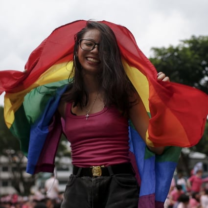 A woman dances with a rainbow flag at the Speaker’s Corner in Hong Lim Park, Singapore. Photo: EPA