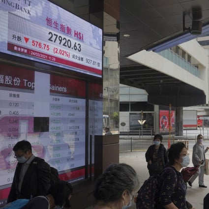 People walk past a bank’s electronic board showing the Hang Seng index in Hong Kong on March 24. Photo: AP