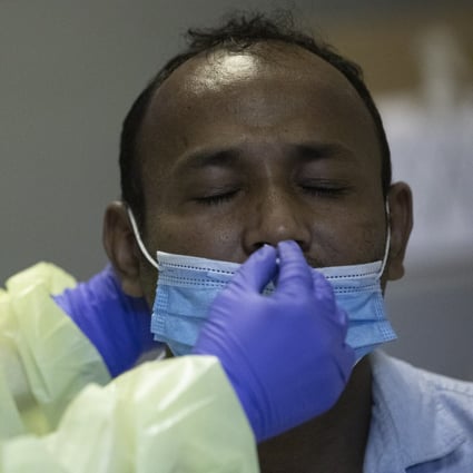 In Singapore, a volunteer performs a coronavirus swab test on a migrant worker. Photo: EPA