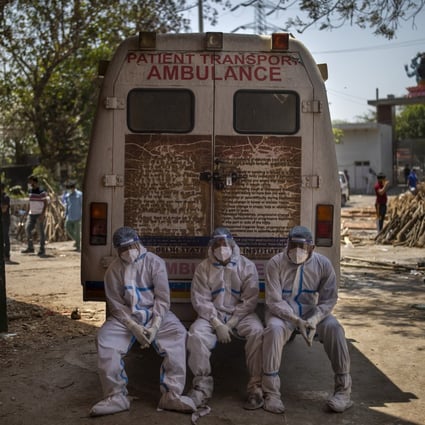 Exhausted workers, who bring dead bodies for cremation, sit on the rear step of an ambulance inside a crematorium in New Delhi, India. Photo: AP