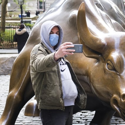 A man in a protective mask takes a selfie with the Charging Bull statue on Broadway in New York. Photo: EPA-EFE