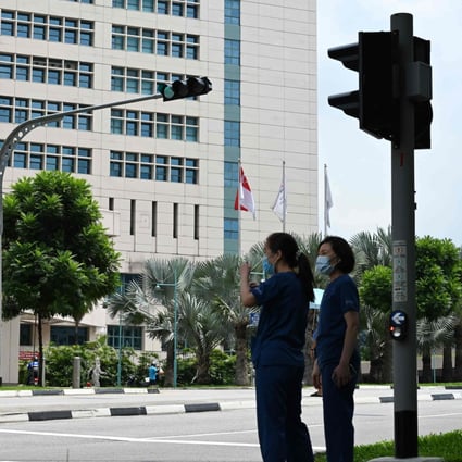 Medical staff wait at a traffic light outside Singapore’s Tan Tock Seng Hospital, as authorities try to contain the spread of a coronavirus cluster detected at the facility. Photo: AFP