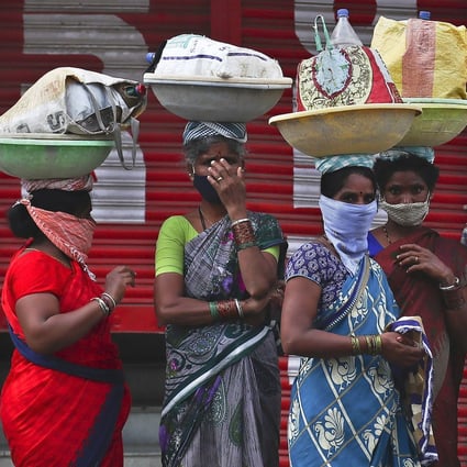 Labourers wearing protective face masks wait for transport to work in Hyderabad, India. Photo: AP