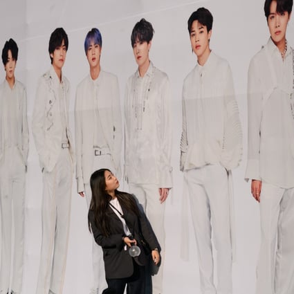 A fan of K-pop group BTS stands against a backdrop featuring an image of the band members as they arrive for the final concert of their world tour at the Olympic stadium in Seoul on October 29, 2019. The tour drew a total audience of more than 2 million at 62 shows in 23 cities, according to Big Hit Entertainment. Photo: AFP