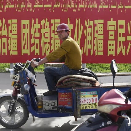 Traffic in Xinjiang passes in front of a banner calling for the stability and development of the Uyghur autonomous region. The Xinjiang government has released a summary of the 2020 census results. Photo: Kyodo