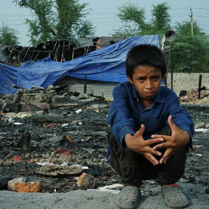 Rohingya refugee Mohammad Ismail sits amid the charred remains of his family’s shelter in New Delhi, in front of the community’s burnt-out mosque. Photo: Adnan Bhat