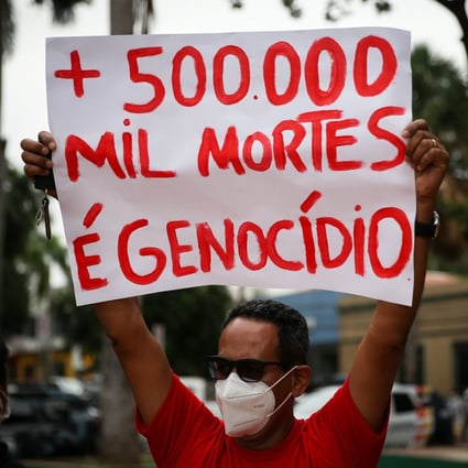 A protester holds a sign reading ‘500,000 deaths and genocide’  in Cuiaba, Brazil on Saturday. Photo: EPA-EFE