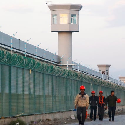 Workers walk along a perimeter fence of what officials call a vocational skills education centre in Dabancheng in Xinjiang. Photo: Reuters