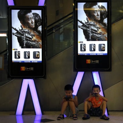 Children use smartphones near monitors displaying a still from Chinese action movie “Wolf Warrior 2” at a cinema in Beijing in August 2017. A new tone of aggression has earned Chinese diplomats the title of “wolf warriors”, after the Rambo-like blockbuster film. Photo: AP 