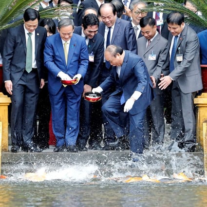 Japanese Prime Minister Yoshihide Suga and his then Vietnamese counterpart Nguyen Xuan Phuc feeding the fish in a pond at the Presidential Palace in Hanoi on October 19, 2020. Photo: Reuters