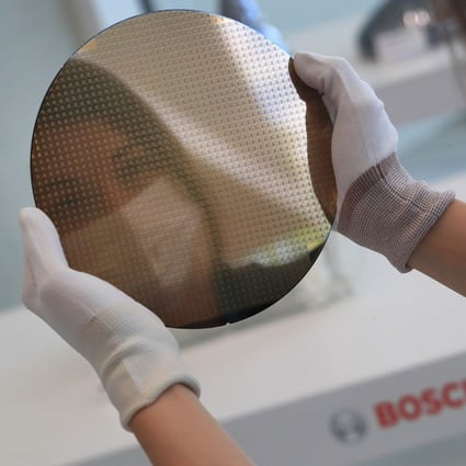 A worker holds a 200mm silicon wafer at the semiconductor fabrication plant operated by Robert Bosch in Dresden, Germany. Photo: Bloomberg
