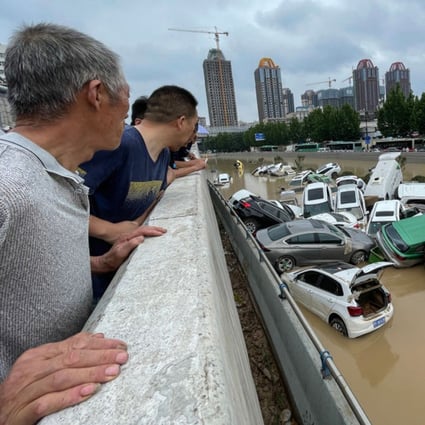 People look out at cars sitting in floodwater after heavy rains hit the city of Zhengzhou in Henan province on July 21. Photo: TNS 
