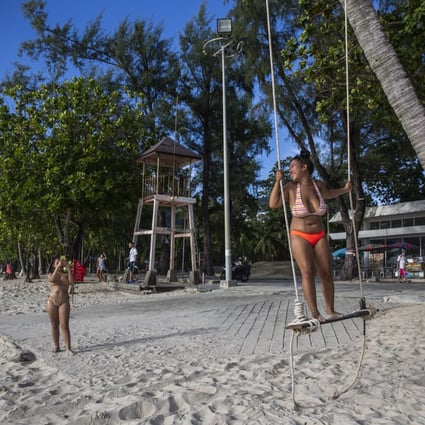 Locals pose for photos on Patong Beach on July 19 in Phuket, Thailand. The island is part of a quarantine-free programme for vaccinated tourists called “Phuket Sandbox”. Photo: Getty Images