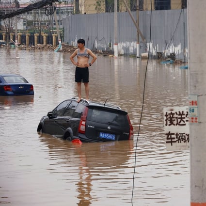 A man stands on a stranded car on a flooded road after heavy rainfall in Zhengzhou, Henan province, China, on July 22. More than 290 have died as a result of the unprecedented flash floods. Scientists warn that more such extreme weather can be expected. Photo: Reuters