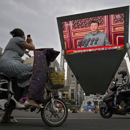 A woman on an electric scooter films Chinese President Xi Jinping on a large screen during an event to commemorate the 100th anniversary of the Communist Party, in Beijing on July 1. Photo: AP