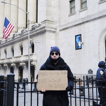 An activist outside the New York Stock Exchange holds a sign as part of a protest calling for higher taxes on the rich, on January 28. The low-rate environment since 2008 has widened wealth and income inequalities. Photo: EPA-EFE