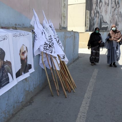 Afghan women approach posters of Taliban leaders and flags in Kabul on August 25. Photo: AP