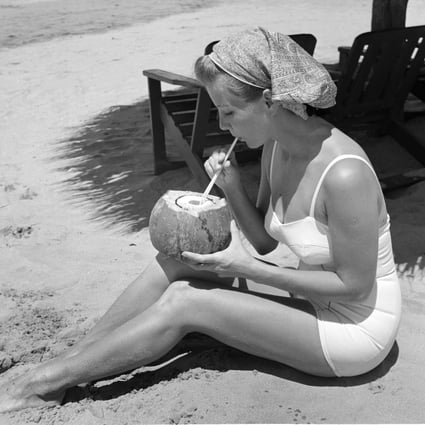 A woman sips from a coconut on a beach in Acapulco, Mexico, in a 1952 photo by Earl Leaf. How the fruit acquired its name in English is a curious tale. Photo: Michael Ochs Archives/Getty Images
